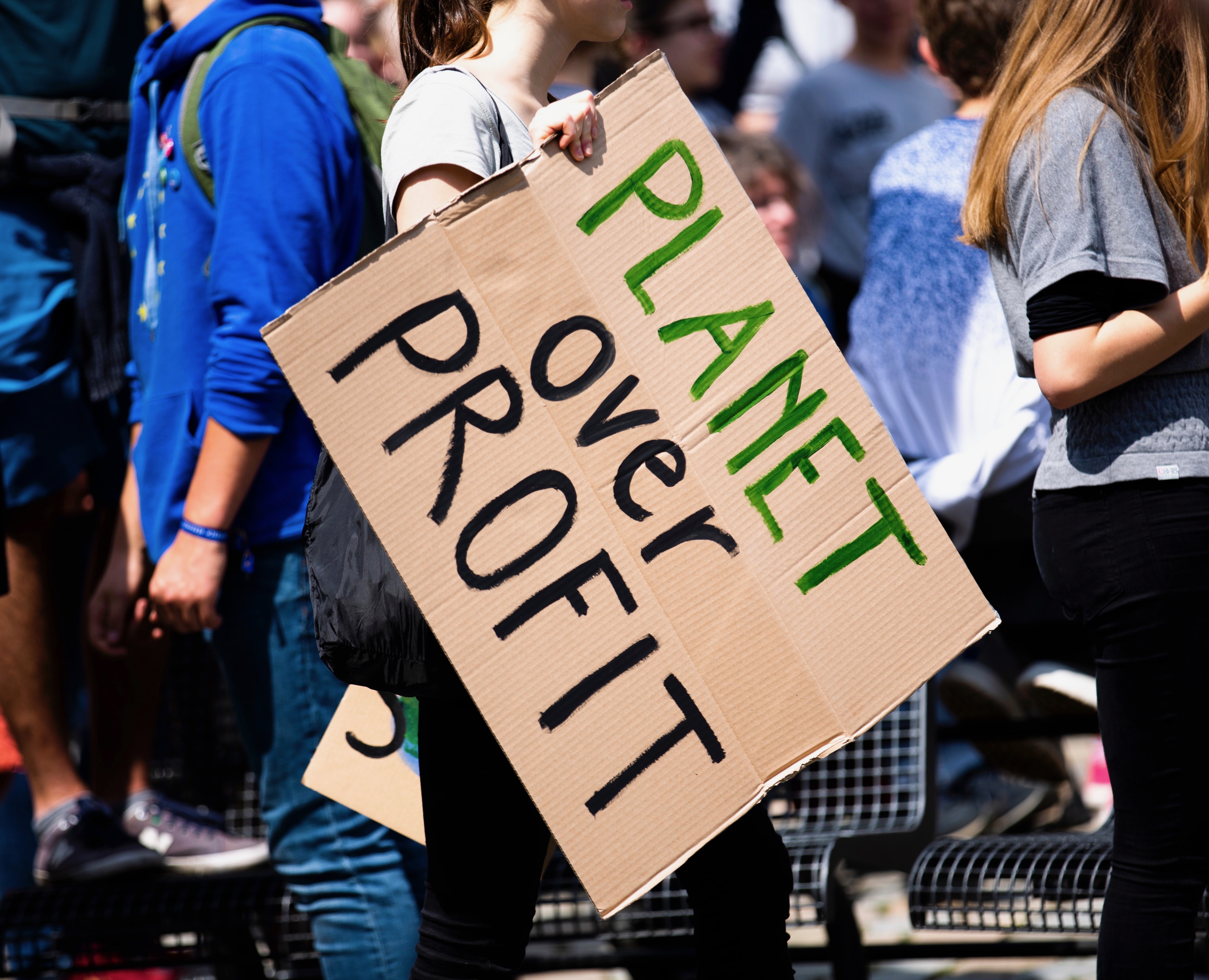Person holding a sign that says 'Planet Over Profit'