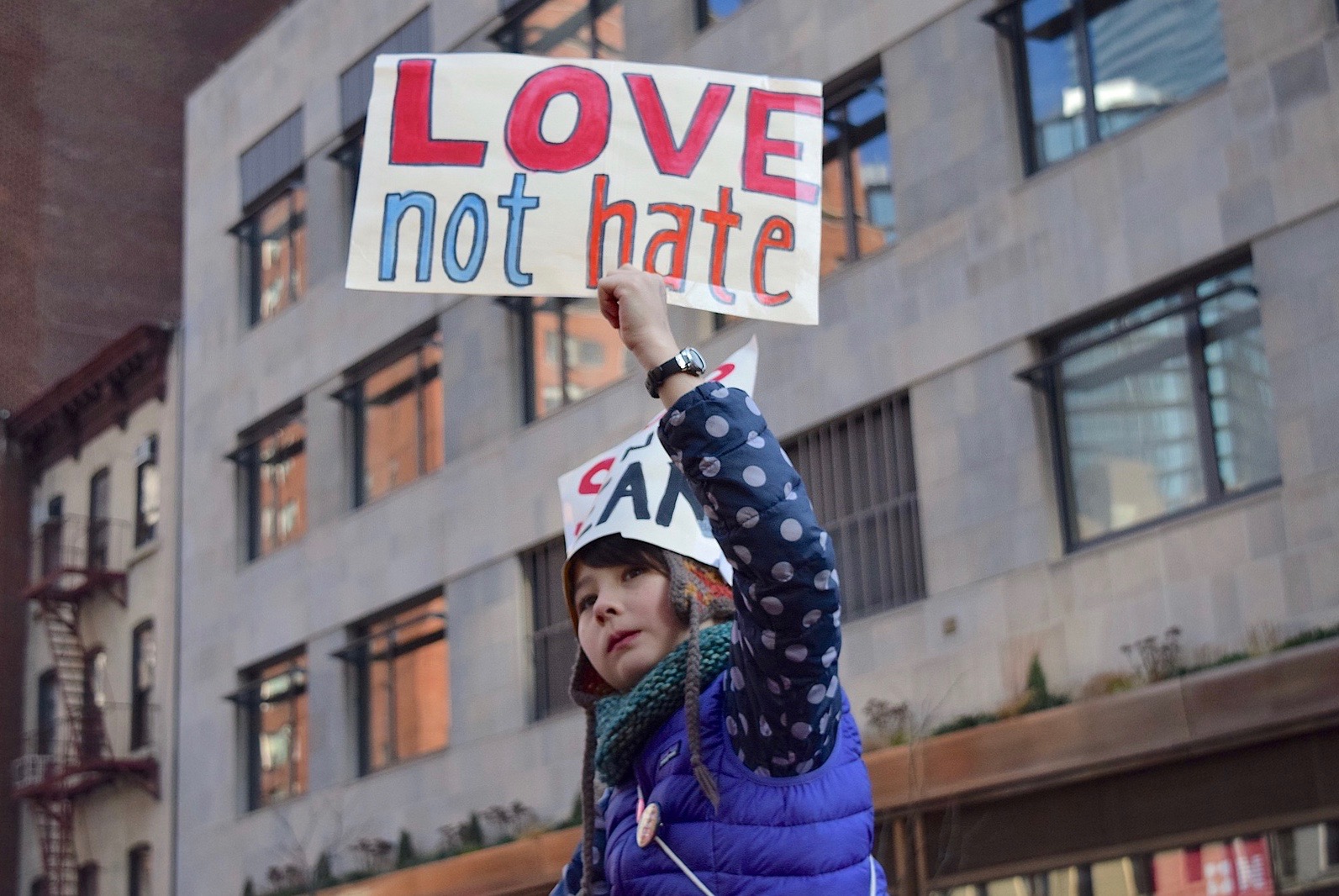 Child holding a sign that says 'Love not hate'